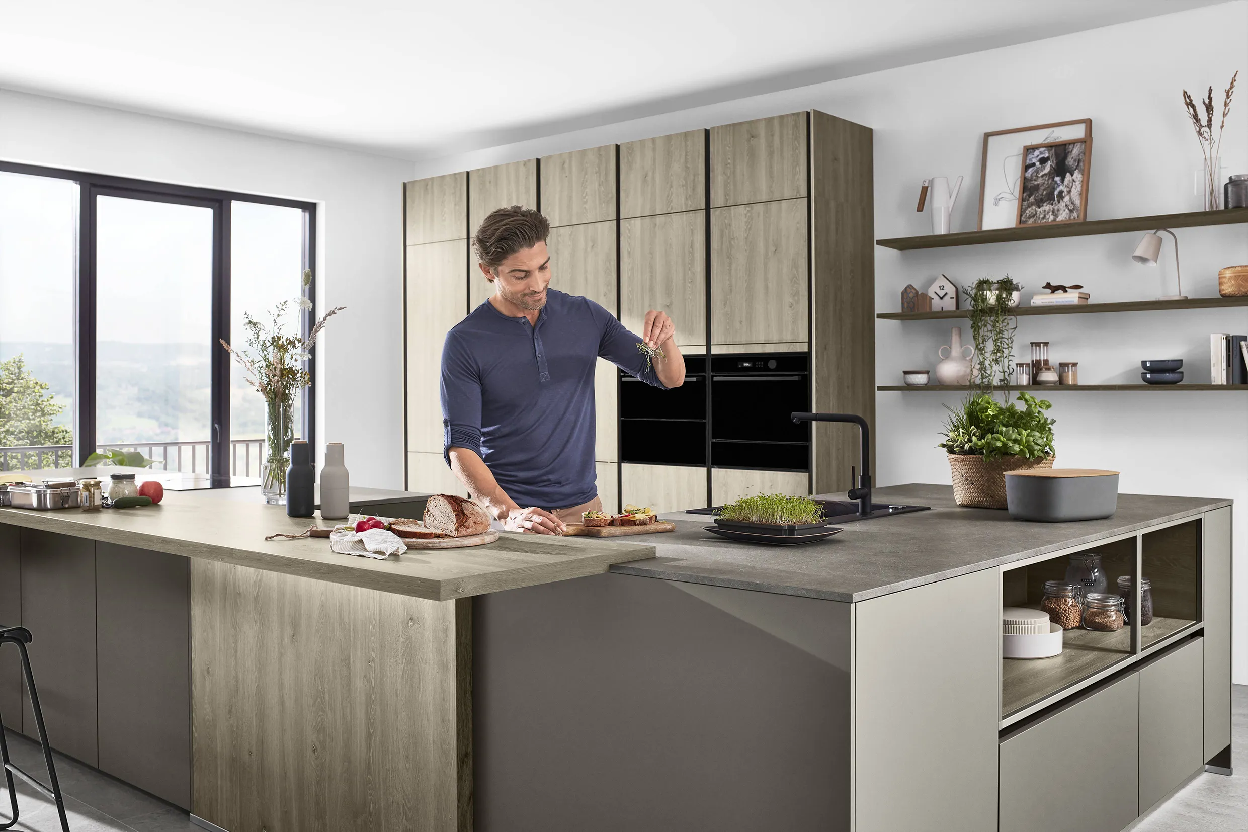Man preparing food in a modern kitchen with German-engineered cabinetry, featuring wood accents and a minimalist design. Man preparing food in a modern kitchen with German-engineered cabinetry, featuring wood accents and a minimalist design.