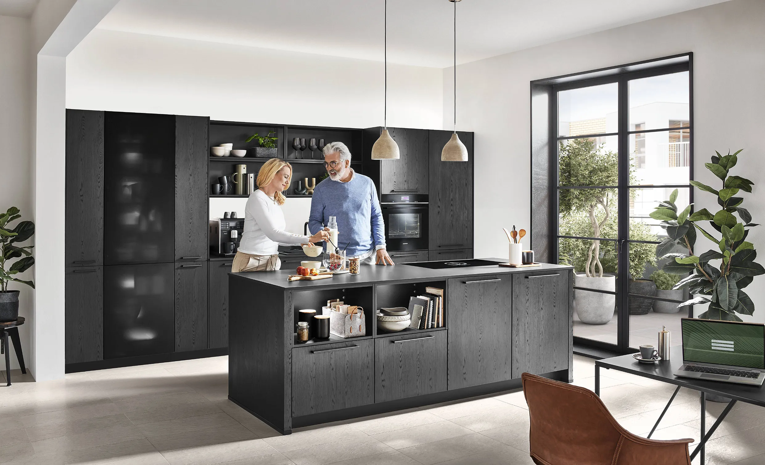 A couple preparing food in a modern kitchen with dark charcoal cabinets, open shelving, and a functional island, featuring a bright and airy layout perfect for social cooking. A couple preparing food in a modern kitchen with dark charcoal cabinets, open shelving, and a functional island, featuring a bright and airy layout perfect for social cooking.