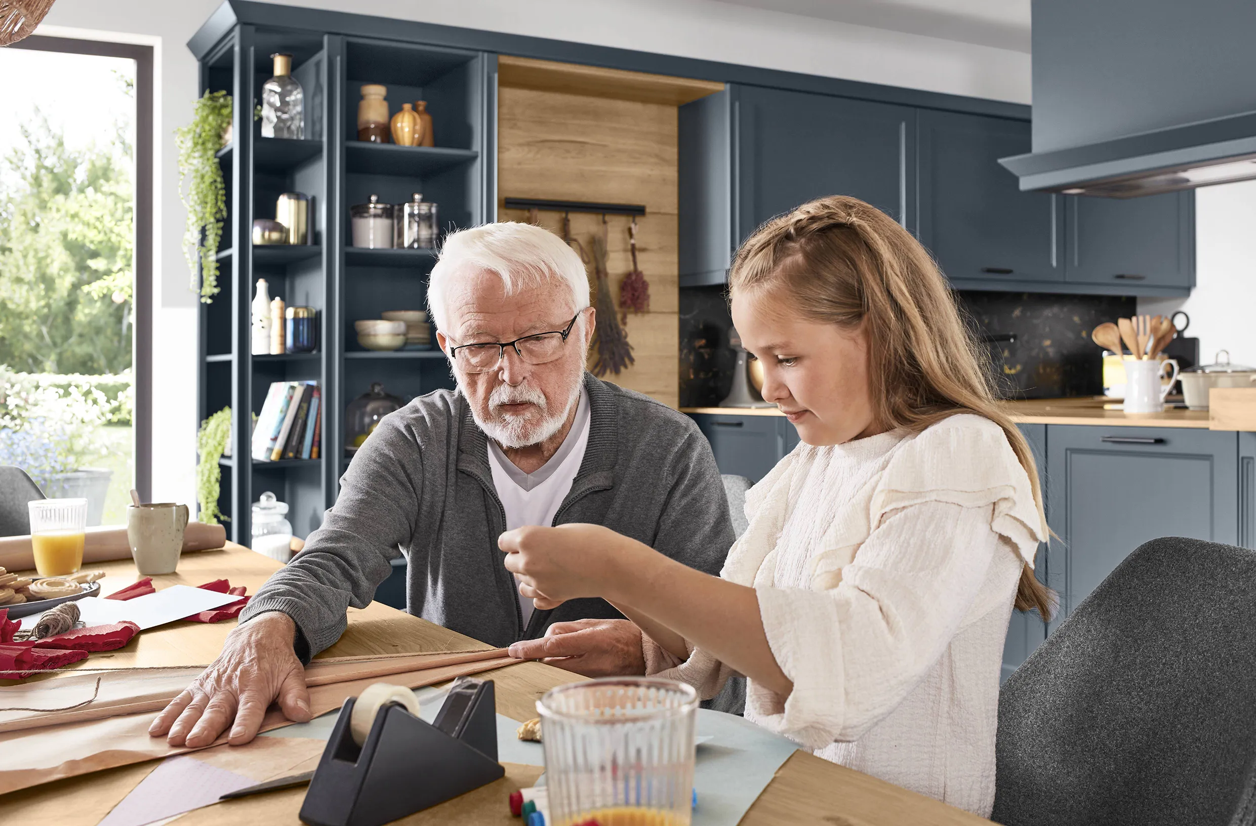 Family-friendly traditional kitchen with deep blue cabinets and natural wood accents, showcasing a grandfather and granddaughter engaged in crafts at the dining table. Family-friendly traditional kitchen with deep blue cabinets and natural wood accents, showcasing a grandfather and granddaughter engaged in crafts at the dining table.
