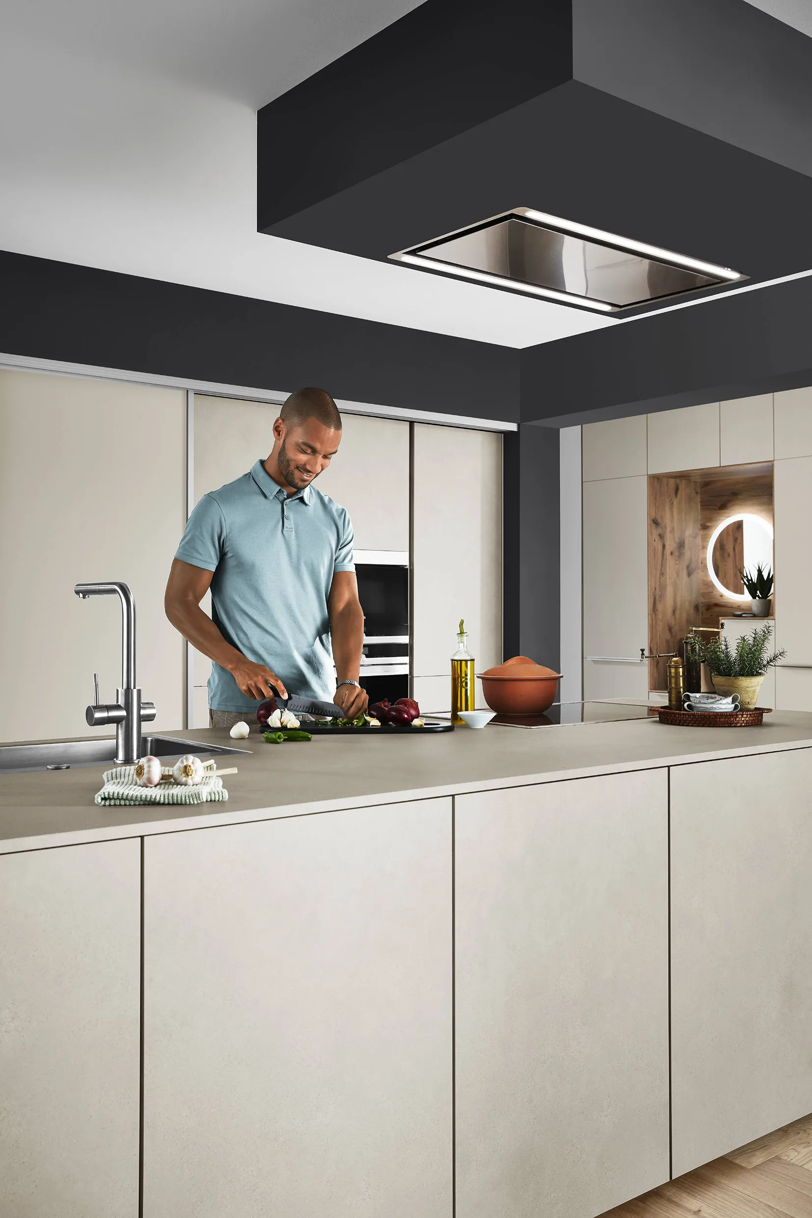 Stylish kitchen with beige cabinetry and a man preparing food on a central island, enhanced by integrated lighting and reflective design elements. Stylish kitchen with beige cabinetry and a man preparing food on a central island, enhanced by integrated lighting and reflective design elements.