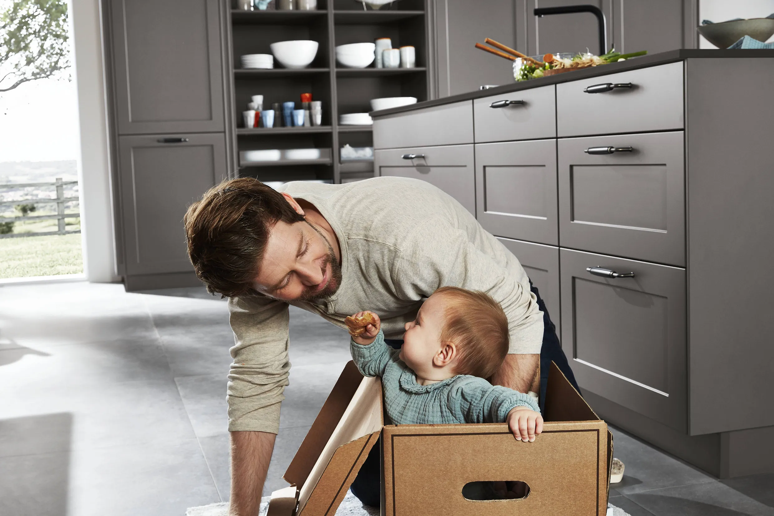 Father playing with his child in a family-friendly kitchen with grey cabinets and spacious design, showcasing a welcoming and adaptable space for growing families. Father playing with his child in a family-friendly kitchen with grey cabinets and spacious design, showcasing a welcoming and adaptable space for growing families.