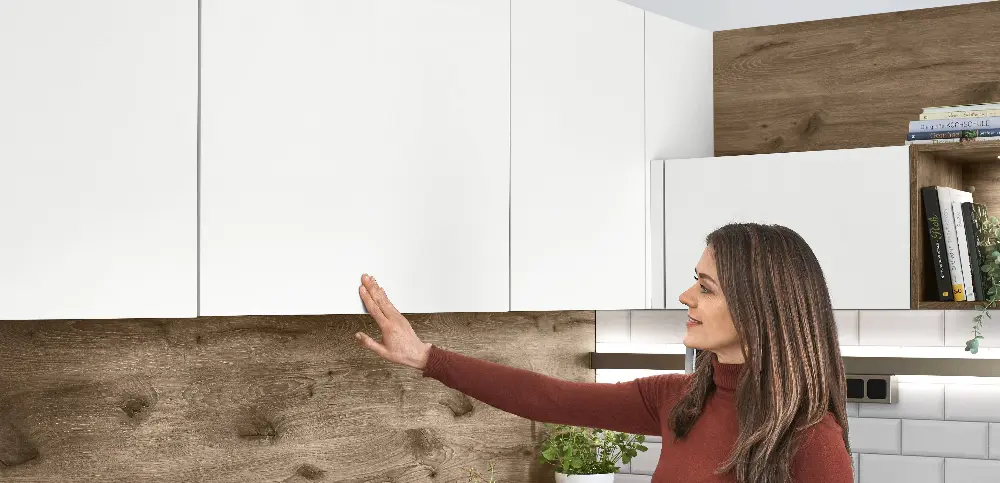 A woman opens a handleless cabinet A woman opens a handleless cabinet